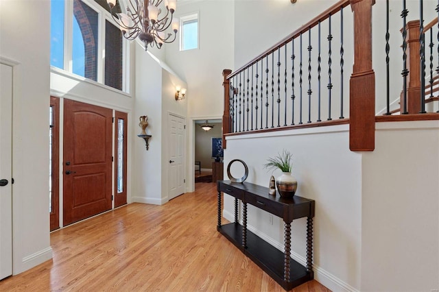 entrance foyer featuring wood finished floors, an inviting chandelier, baseboards, a towering ceiling, and stairs