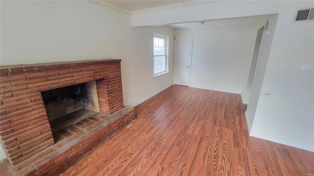 unfurnished living room featuring a brick fireplace, ornamental molding, and hardwood / wood-style flooring