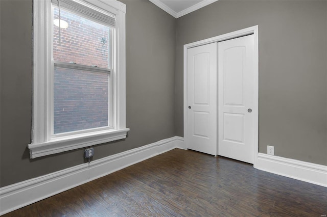 unfurnished bedroom featuring ornamental molding, dark hardwood / wood-style floors, and a closet