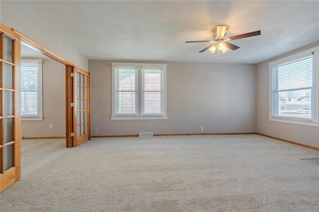 unfurnished room featuring light carpet, a wealth of natural light, french doors, and ceiling fan