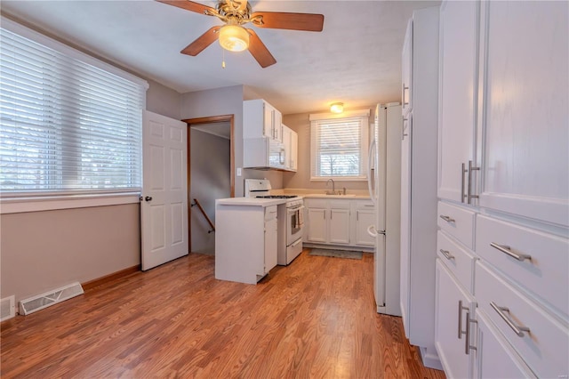 kitchen featuring sink, white cabinetry, ceiling fan, white appliances, and light hardwood / wood-style floors