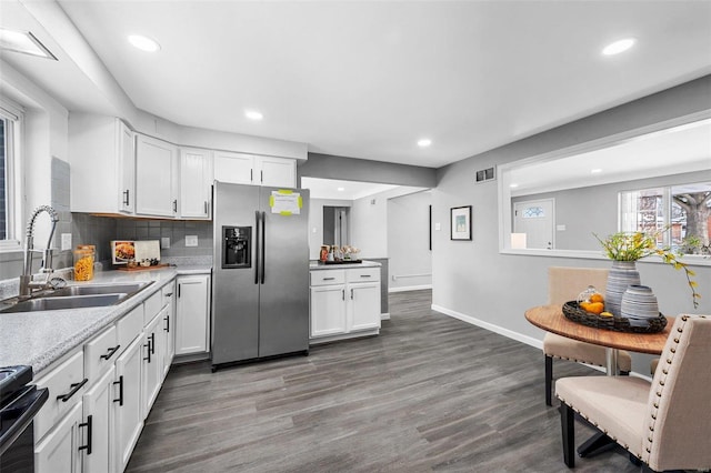 kitchen with sink, stainless steel fridge, white cabinets, and range