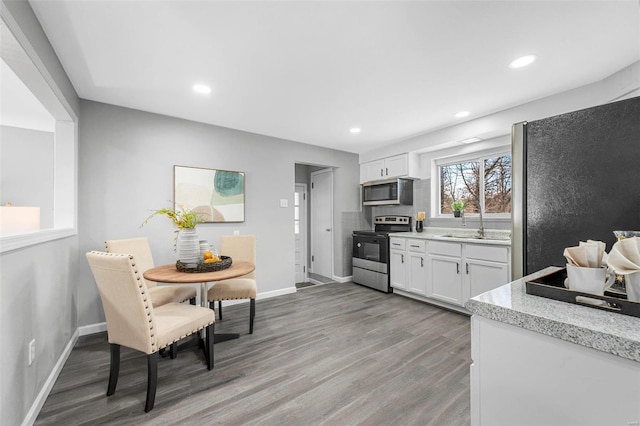 kitchen featuring stainless steel appliances, hardwood / wood-style floors, and white cabinets