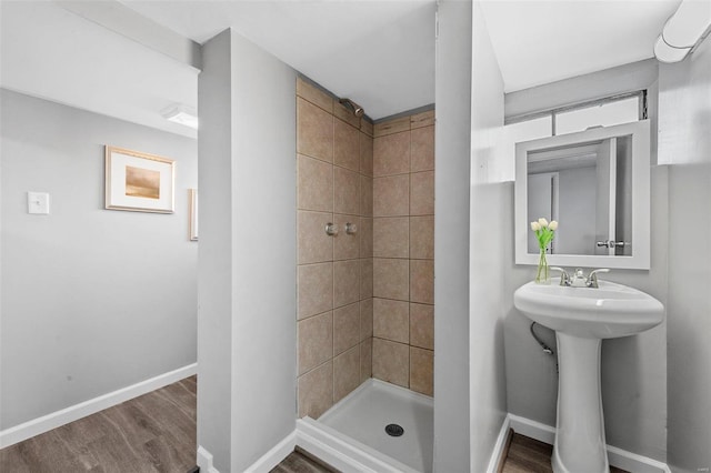 bathroom with a tile shower, sink, and hardwood / wood-style flooring