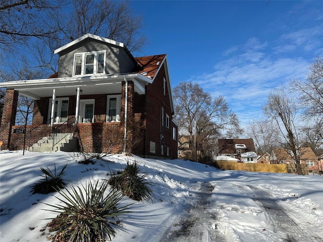 snow covered property with covered porch