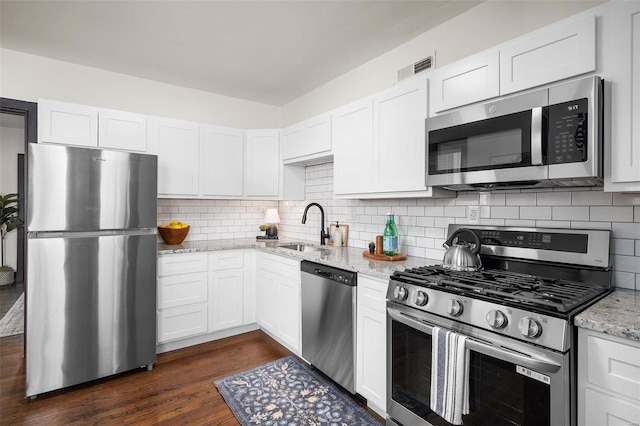 kitchen with stainless steel appliances, white cabinets, light stone counters, tasteful backsplash, and dark hardwood / wood-style floors