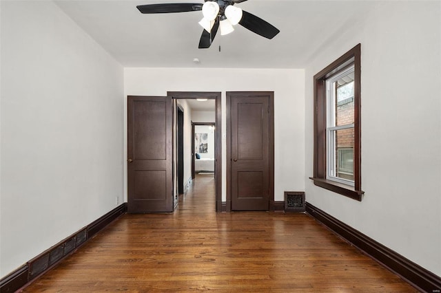 spare room featuring a baseboard heating unit, ceiling fan, and dark hardwood / wood-style floors