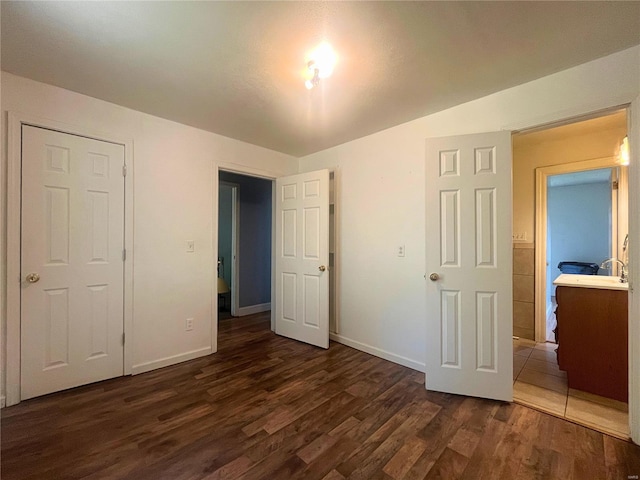 unfurnished bedroom with dark wood-type flooring, connected bathroom, and a closet