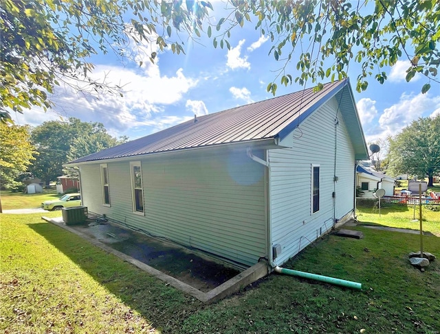 view of side of property featuring a yard and central AC