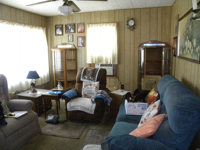 sitting room featuring wood walls, ceiling fan, cooling unit, and a healthy amount of sunlight