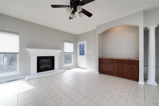 unfurnished living room with light tile patterned floors, ceiling fan, and ornate columns