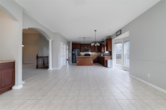 kitchen featuring ornate columns, light tile patterned flooring, hanging light fixtures, a center island, and black fridge