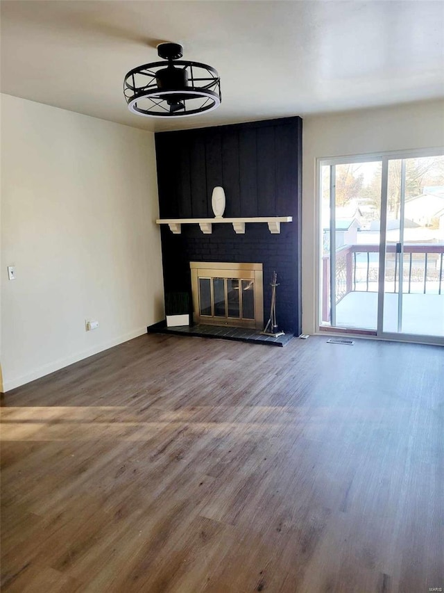 unfurnished living room featuring hardwood / wood-style flooring and a brick fireplace