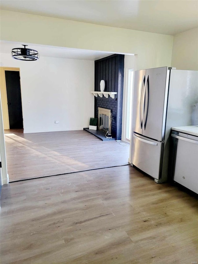 kitchen featuring light hardwood / wood-style flooring, a fireplace, and stainless steel refrigerator