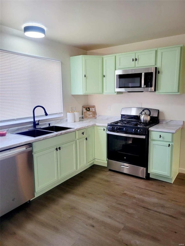 kitchen with sink, stainless steel appliances, dark hardwood / wood-style floors, and green cabinetry