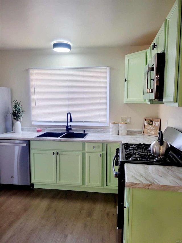 kitchen with stainless steel appliances, sink, dark hardwood / wood-style floors, and green cabinetry