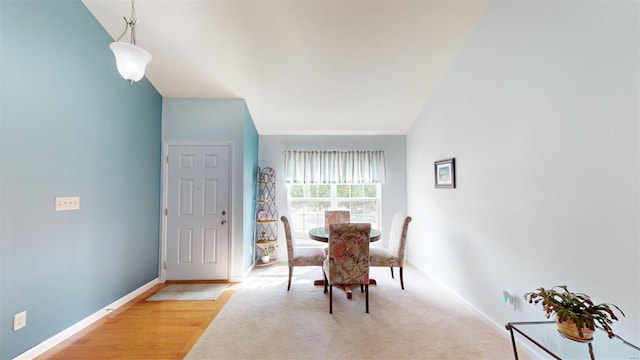 dining space with high vaulted ceiling and light hardwood / wood-style floors