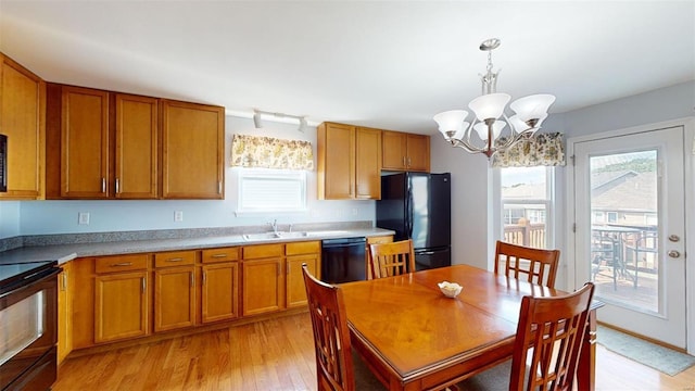 kitchen with sink, an inviting chandelier, light hardwood / wood-style flooring, hanging light fixtures, and black appliances