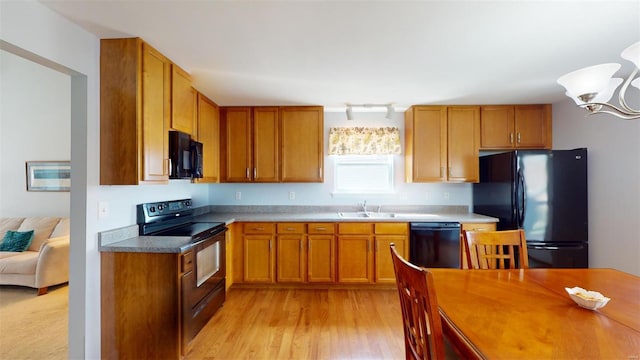 kitchen with sink, light hardwood / wood-style flooring, track lighting, black appliances, and a notable chandelier