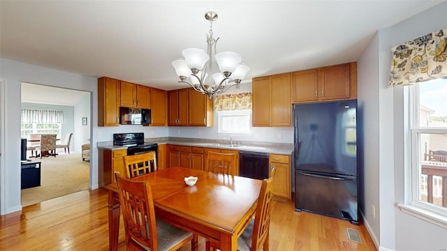 kitchen featuring a wealth of natural light, decorative light fixtures, black appliances, an inviting chandelier, and sink