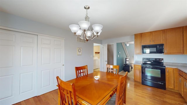 dining area featuring a notable chandelier, light hardwood / wood-style floors, and washer / dryer