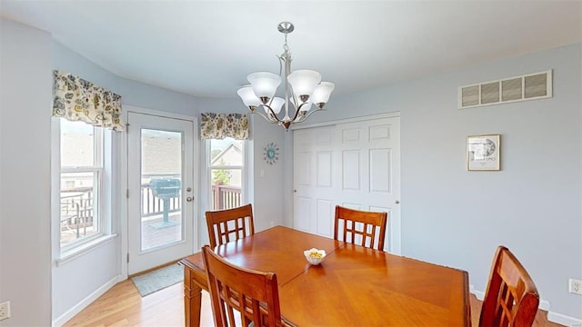 dining space featuring light hardwood / wood-style flooring, an inviting chandelier, and plenty of natural light