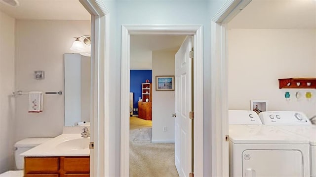 washroom featuring washing machine and clothes dryer, light carpet, and sink