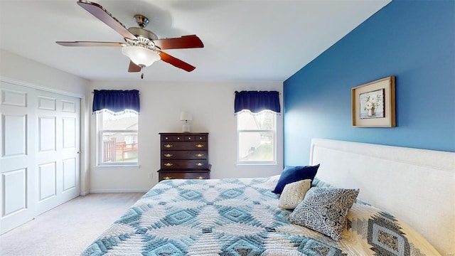 carpeted bedroom with ceiling fan, a closet, and multiple windows