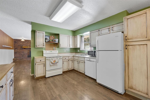 kitchen with sink, white appliances, wood walls, and a textured ceiling