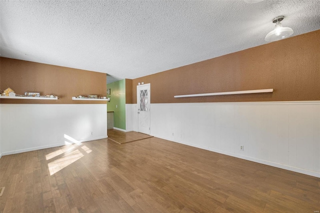 spare room with wood walls, a textured ceiling, and hardwood / wood-style flooring