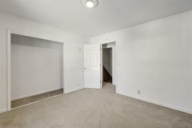 unfurnished bedroom featuring light colored carpet, a closet, and a textured ceiling