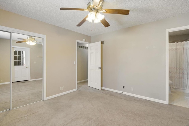 unfurnished bedroom with a textured ceiling, ceiling fan, light colored carpet, and ensuite bath