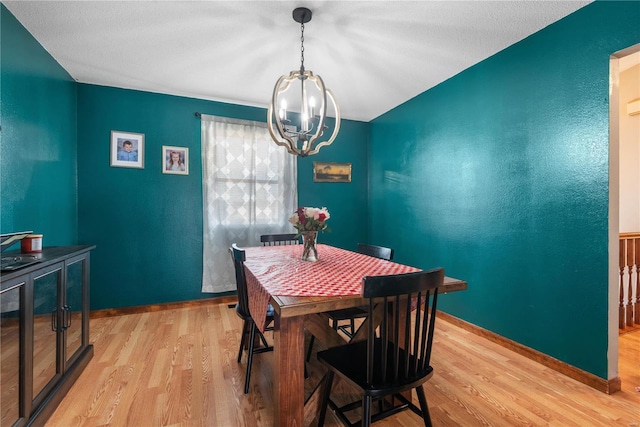 dining space featuring a textured ceiling, an inviting chandelier, and light hardwood / wood-style floors