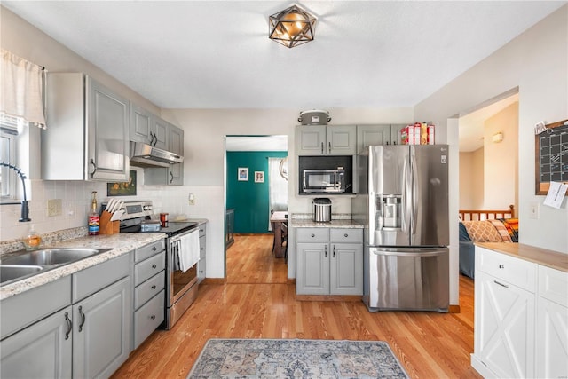 kitchen with light wood-type flooring, stainless steel appliances, gray cabinetry, and sink