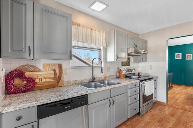 kitchen with gray cabinets, appliances with stainless steel finishes, light hardwood / wood-style floors, and sink