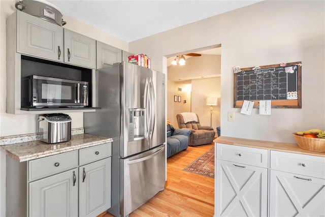 kitchen with ceiling fan, light wood-type flooring, appliances with stainless steel finishes, and gray cabinets