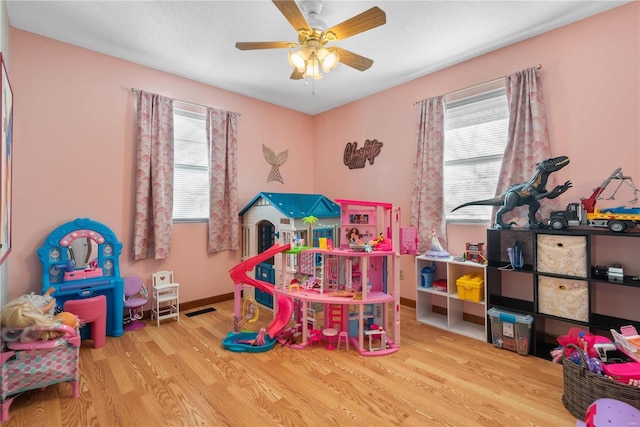 game room featuring light wood-type flooring, ceiling fan, and plenty of natural light