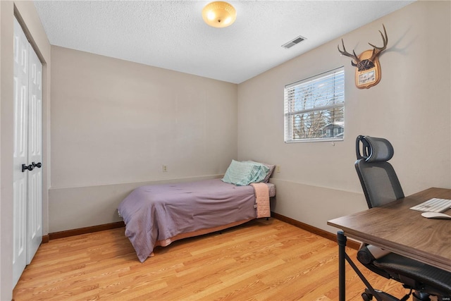 bedroom with light wood-type flooring, a closet, and a textured ceiling