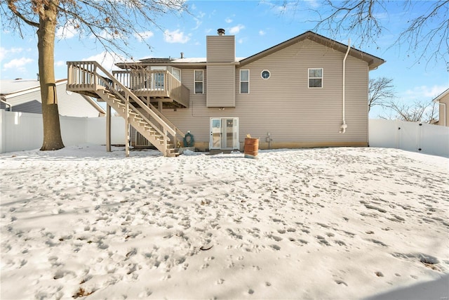 snow covered house with a wooden deck