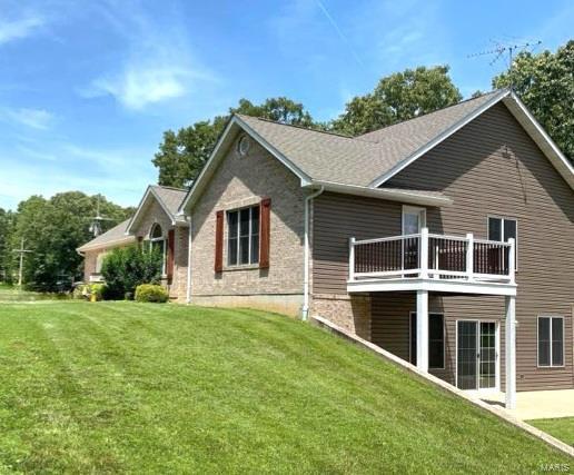 rear view of house featuring a balcony and a lawn