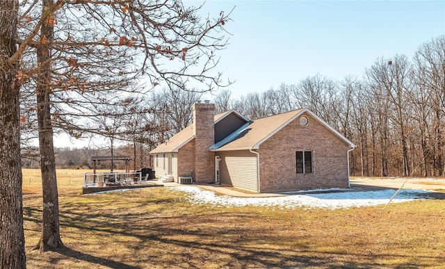 view of property exterior featuring brick siding, a lawn, a chimney, and a patio