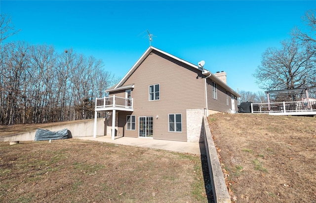 back of house featuring a patio area, a lawn, and a chimney