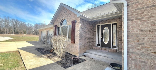 doorway to property with brick siding, roof with shingles, and an attached garage