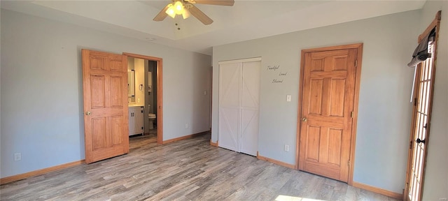 unfurnished bedroom with light wood-type flooring, a closet, baseboards, and a tray ceiling