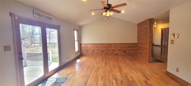 unfurnished room with a healthy amount of sunlight, light wood finished floors, and vaulted ceiling