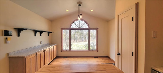 unfurnished dining area featuring lofted ceiling, light wood-style floors, baseboards, and a wealth of natural light