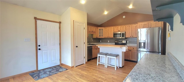 kitchen with a center island, light countertops, backsplash, appliances with stainless steel finishes, and light wood-style floors