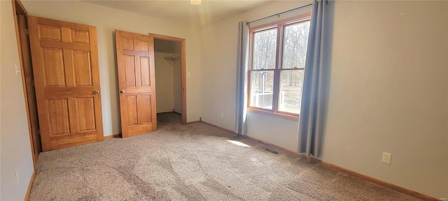 unfurnished bedroom featuring baseboards, multiple windows, visible vents, and carpet flooring