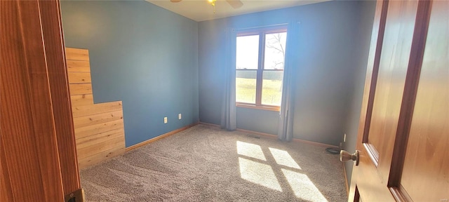 carpeted empty room featuring ceiling fan and baseboards