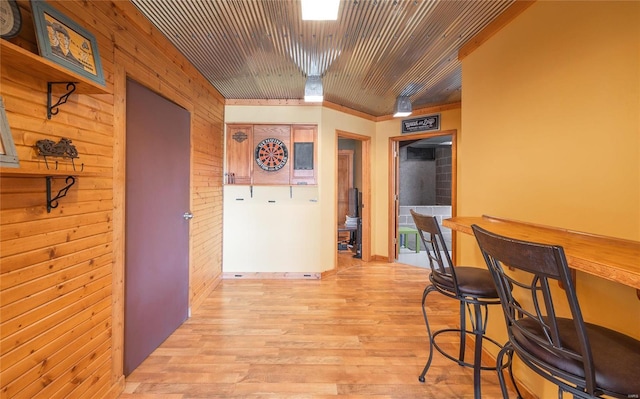 dining area featuring wooden ceiling, wooden walls, and light wood finished floors